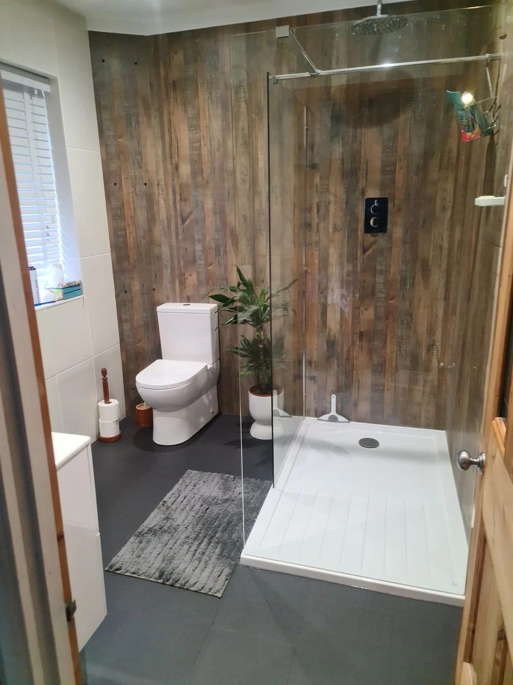Walk-in shower with rustic reclaimed-wood panelling, black controls and a slate grey floor