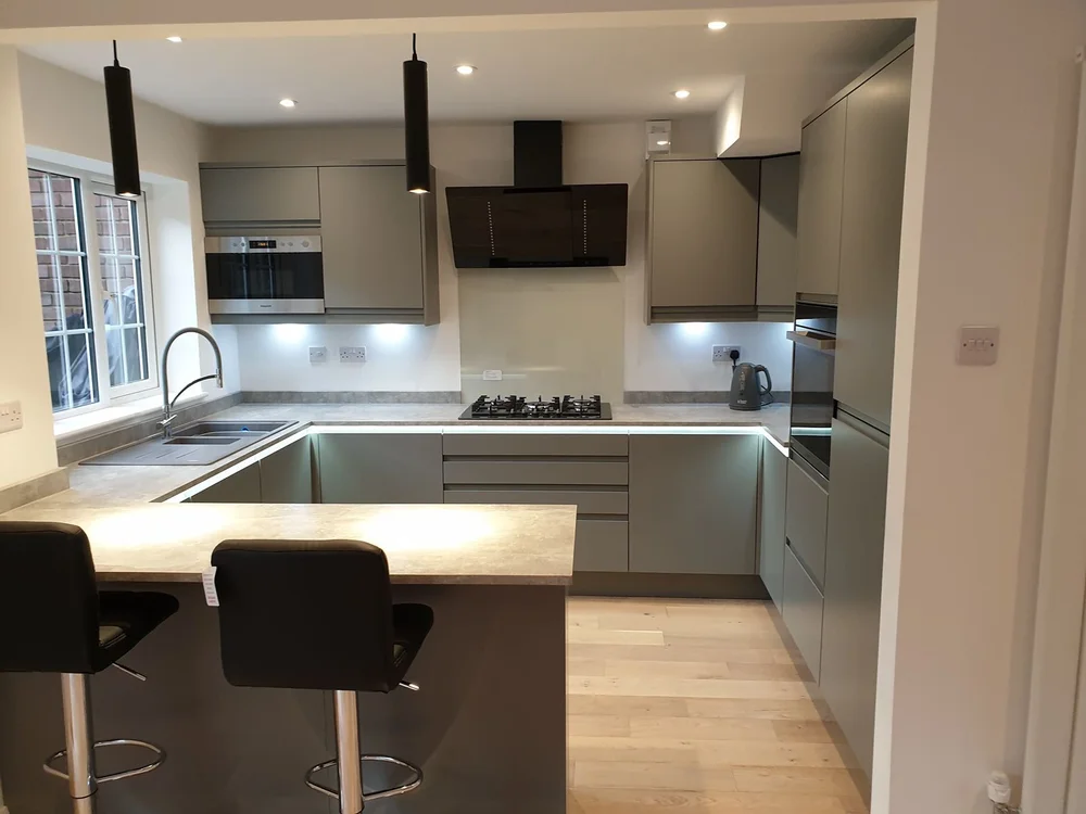Handleless graphite kitchen with an oak-effect worktop and black pendant lights, fitted by Chiltern Installations