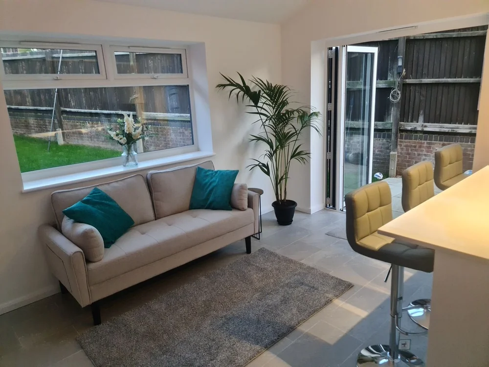 Bright living space after refurbishment, with bifold doors to the garden, a sofa and a breakfast bar